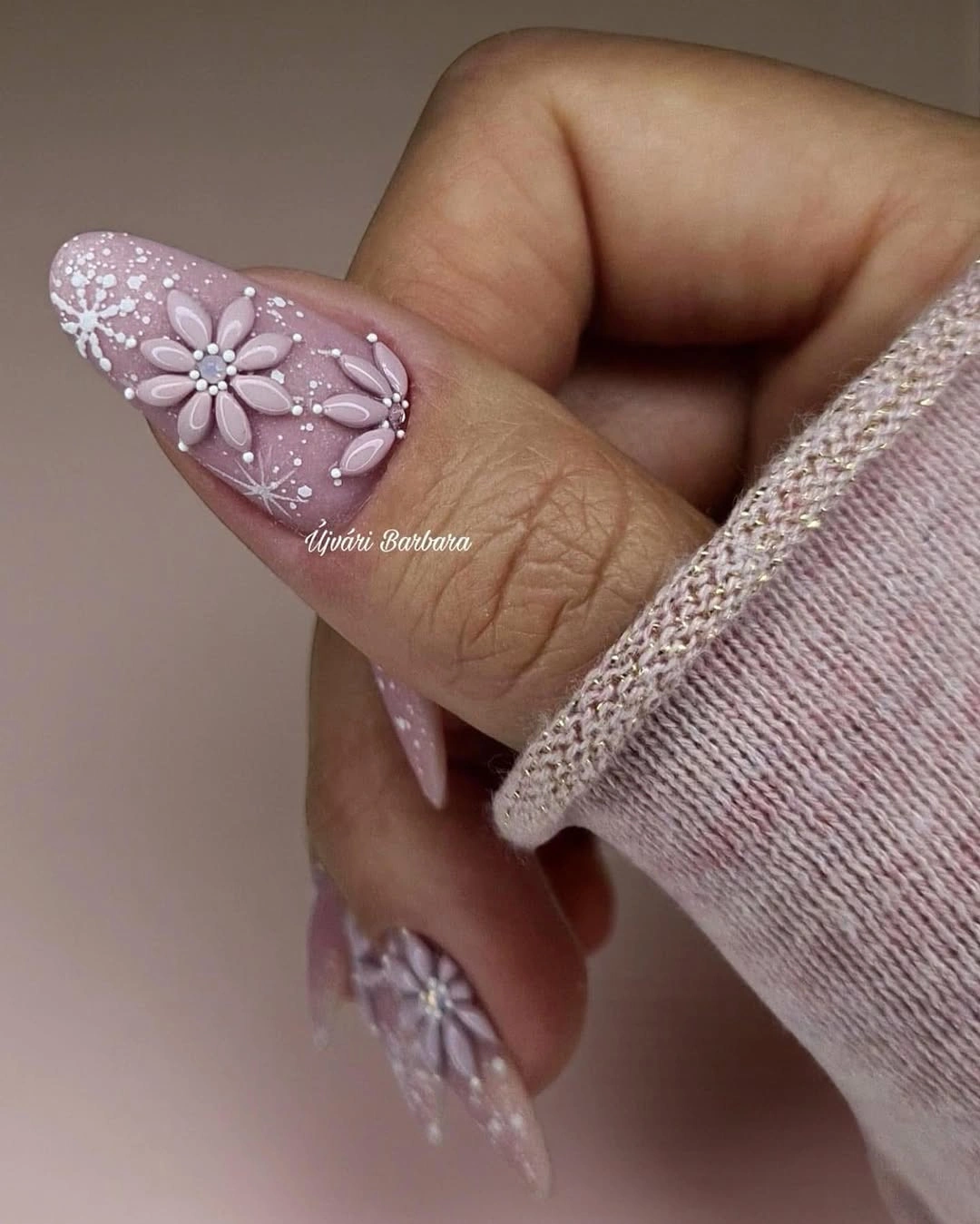 Long pointed mauve nails with raised-looking white flowers and delicate snowflake details