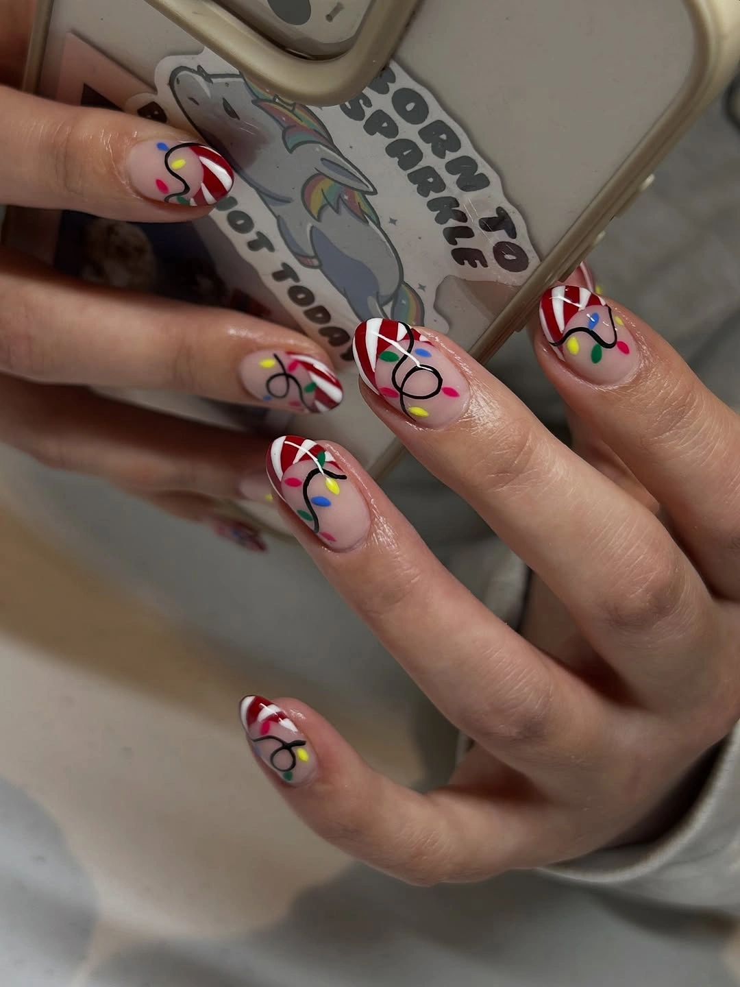 Square pink nails with candy stripes and colorful string light designs