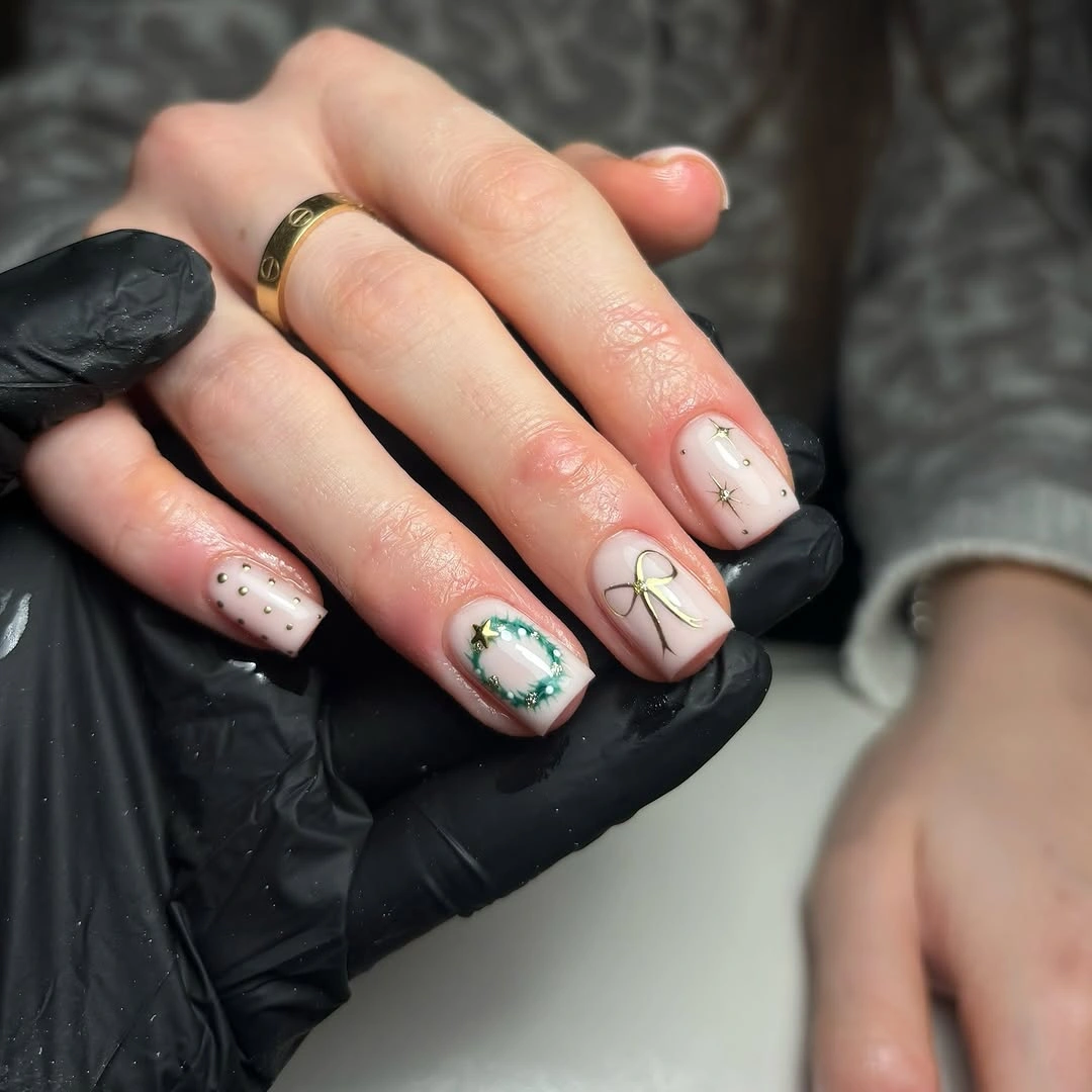 Short blush pink square nails with green wreath and fine gold bows