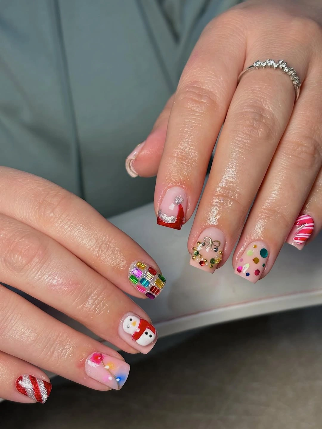 Short nails with candy stripes, colorful dots and small illustrated holiday character