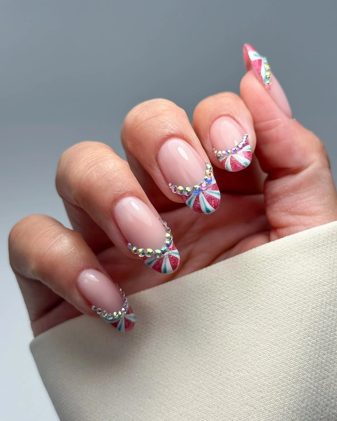Long pointed pink nails with multicolored curved stripes and small reflective accents
