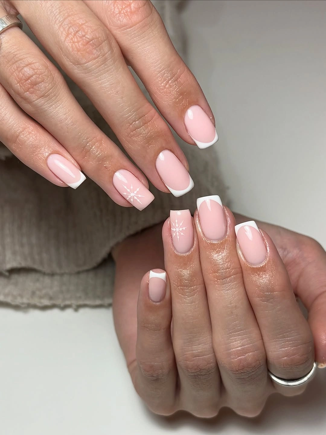 Soft-square pale pink nails with thin white French tips and small starburst accents