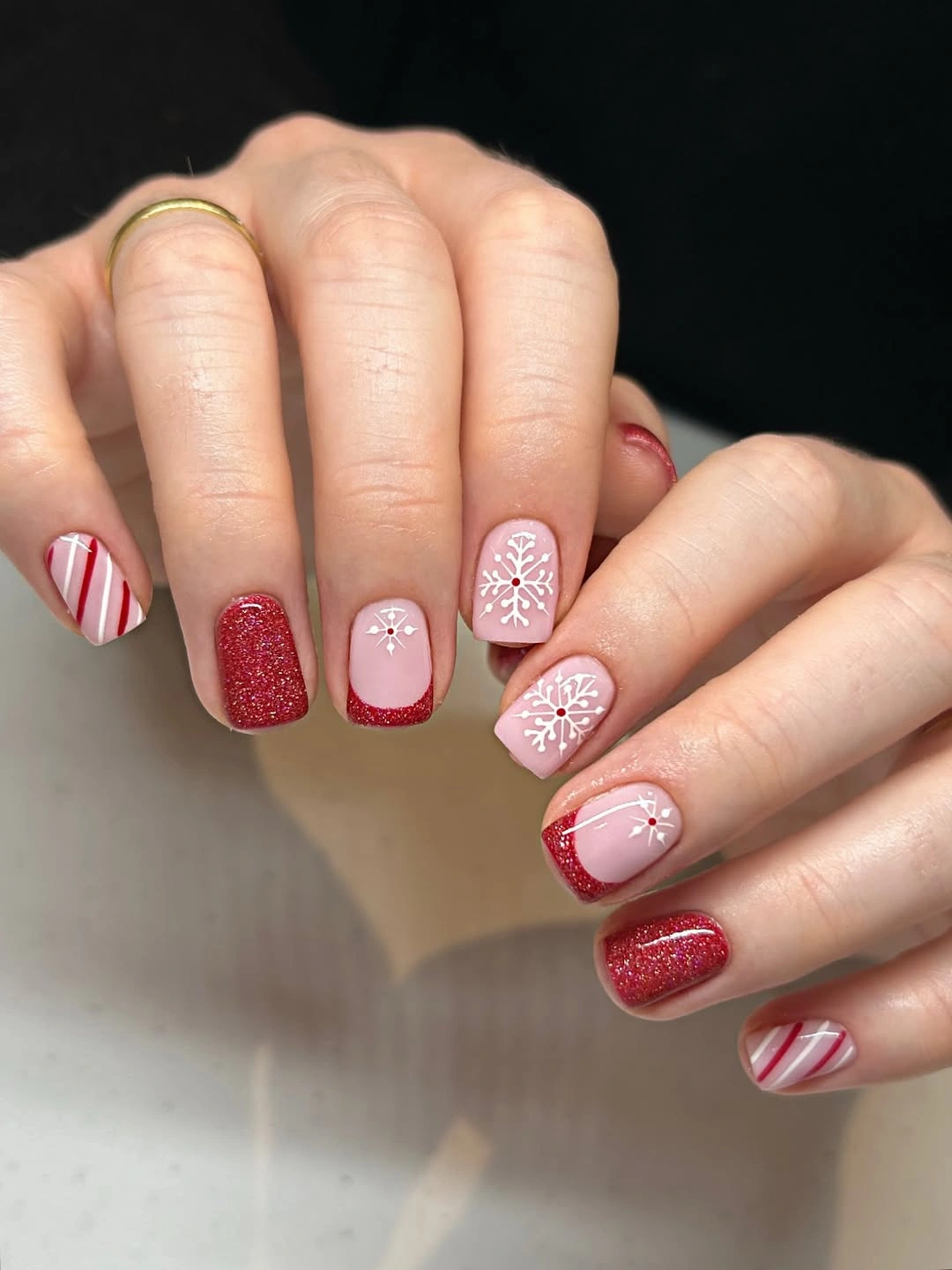 Short red glitter nails with white snowflakes, candy stripes and sparkling French tips