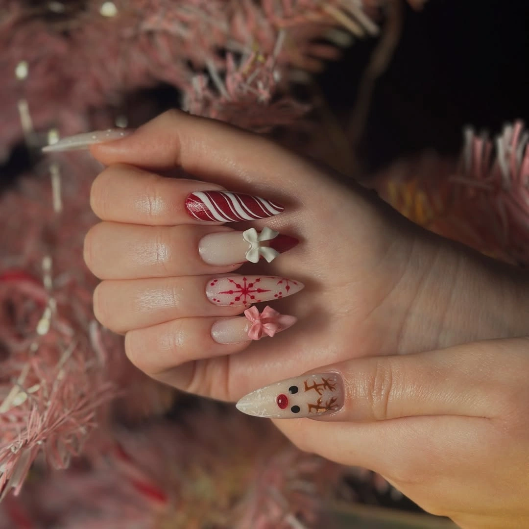 Long pointed almond nails with reindeer, red stripes and raised-looking decorative accents