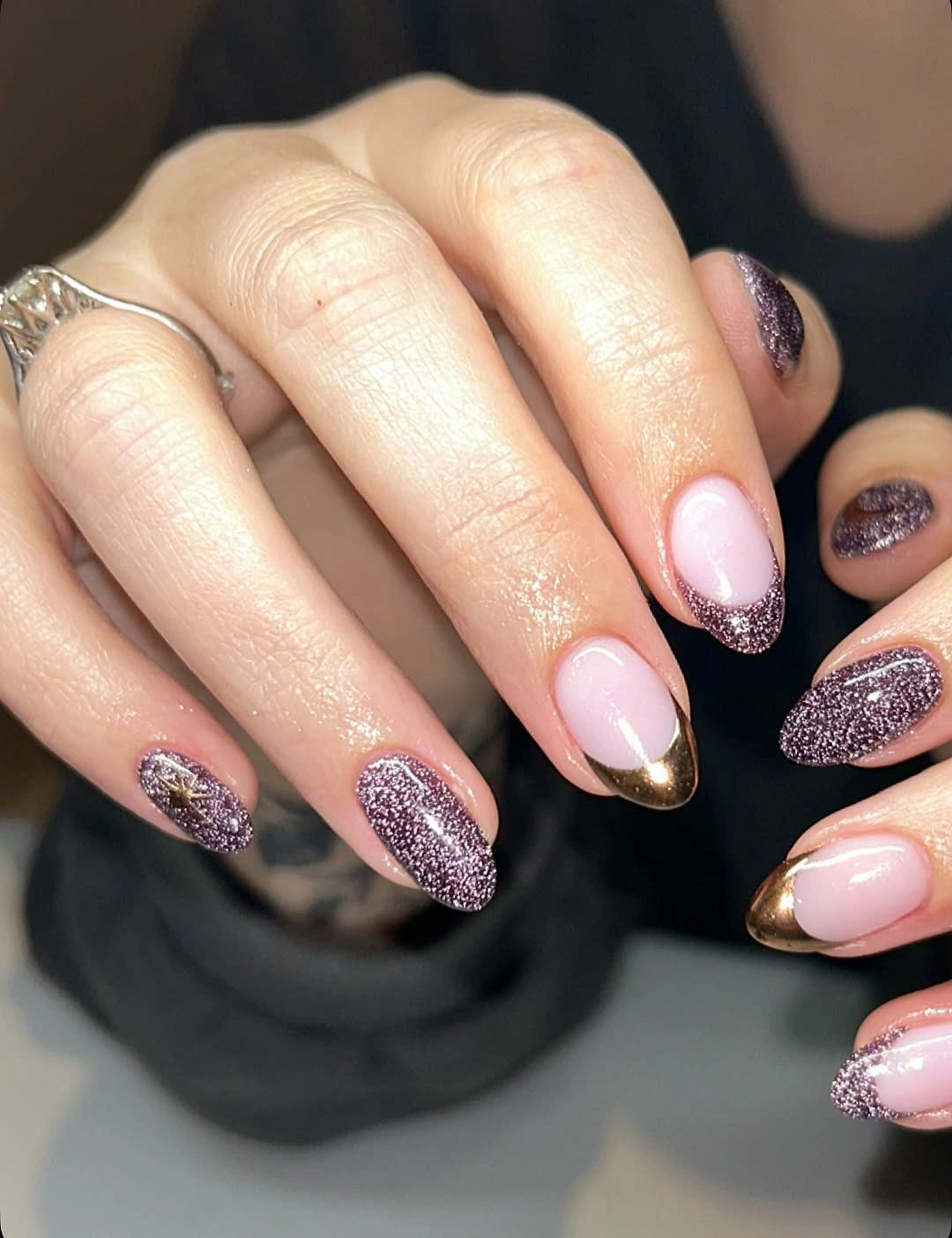 Almond nails with plum glitter, translucent pink bases and bronze-gold French tips