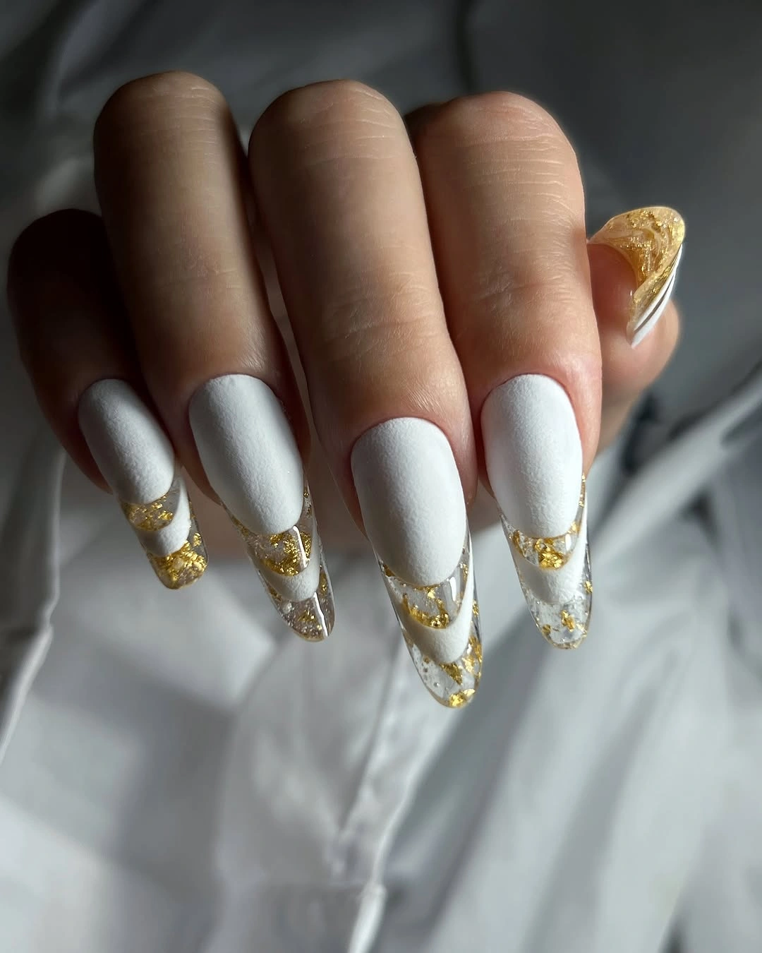 Long pointed white nails with translucent-looking gold-accented tips