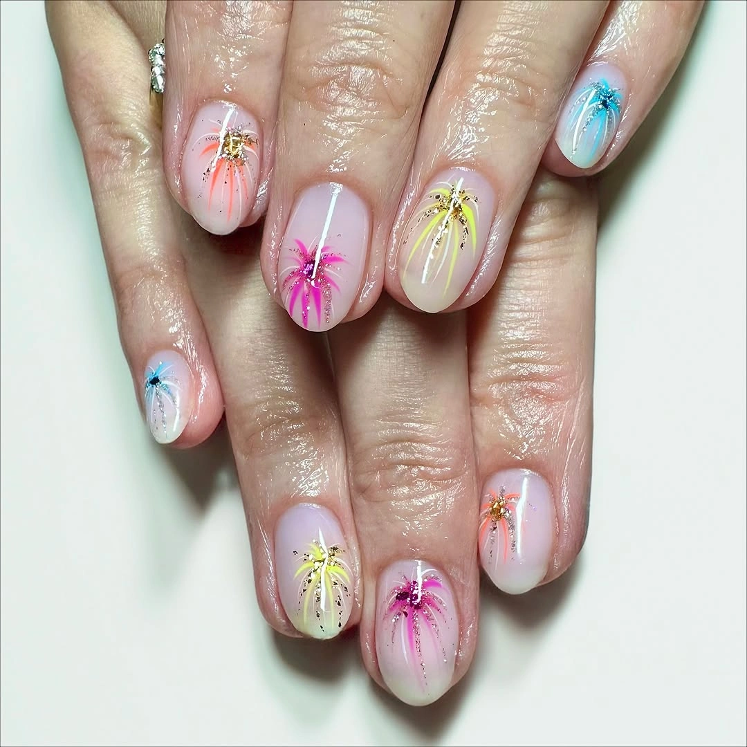 Pale pink and lilac nails with multicolored painted starburst-like motifs