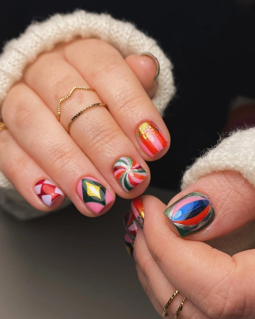 Short rounded nails with colorful curves, geometric shapes, stripes, and a spiral