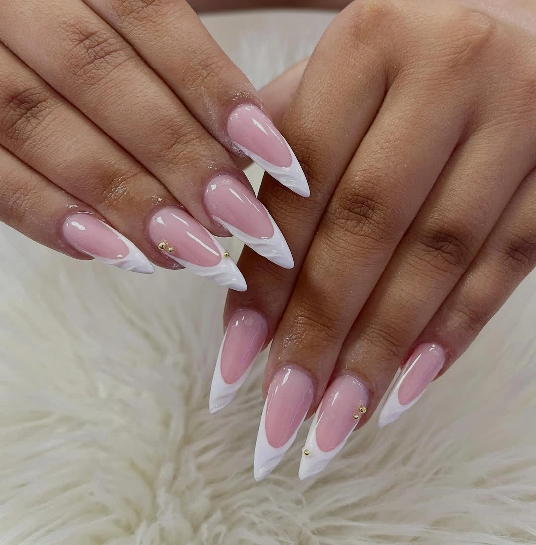 Long pink almond nails with diagonal white tips and tiny gold accents